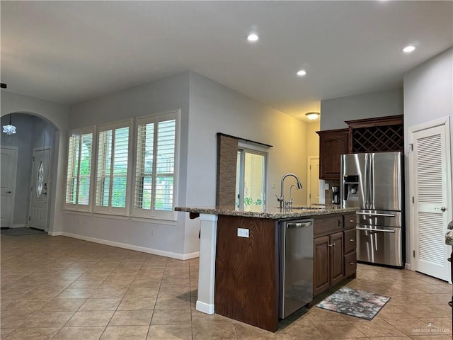 kitchen featuring appliances with stainless steel finishes, light tile patterned floors, a kitchen island with sink, and sink