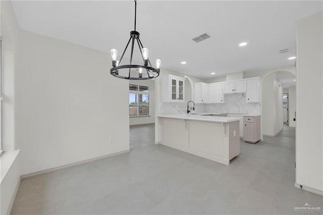 3621 Xenops Ave, Mcallen, TX 78504 - kitchen with visible vents, an inviting chandelier, a peninsula, a kitchen bar, and arched walkways