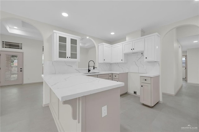 3621 Xenops Ave, Mcallen, TX 78504 - kitchen featuring a peninsula, light stone countertops, arched walkways, tasteful backsplash, and a sink