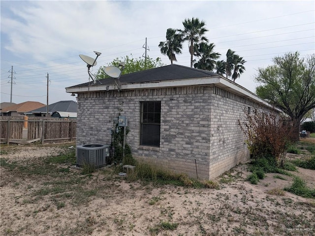 view of home's exterior with brick siding, fence, and central air condition unit