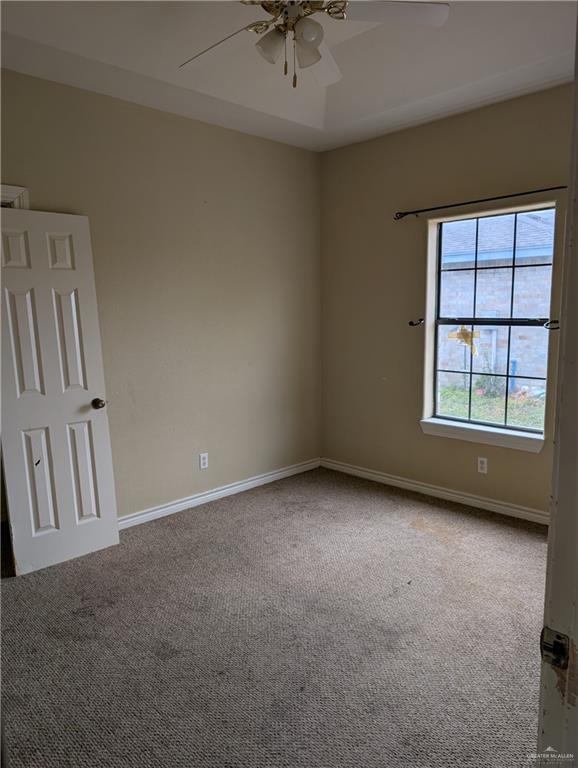 empty room featuring ceiling fan, carpet, and baseboards