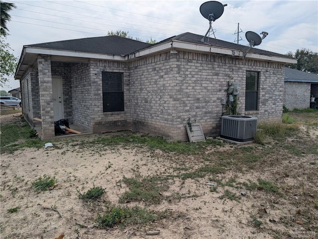 rear view of property with central AC unit and brick siding