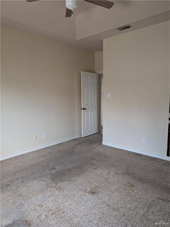 carpeted spare room featuring visible vents, ceiling fan, and baseboards