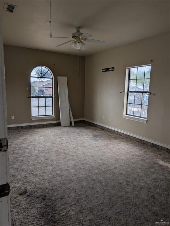 carpeted spare room with a ceiling fan, visible vents, and baseboards