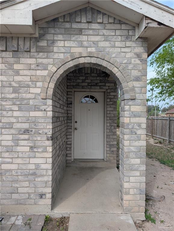 property entrance featuring brick siding and fence