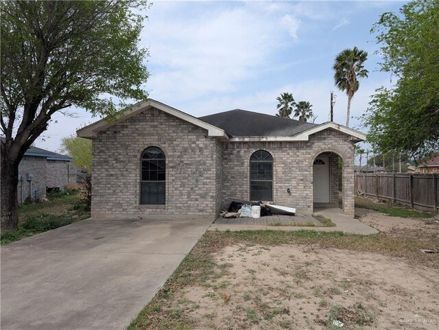 ranch-style home featuring brick siding and fence