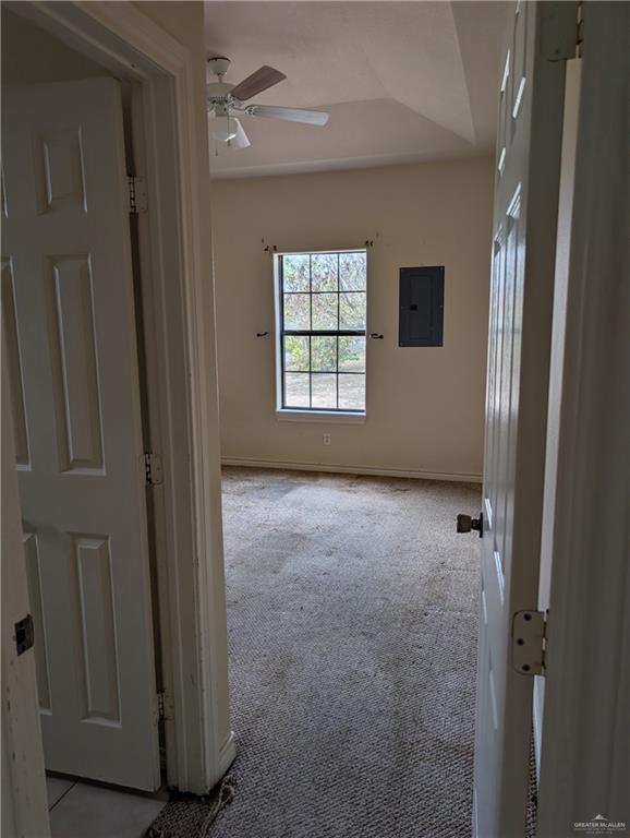 spare room featuring a ceiling fan, baseboards, electric panel, and carpet flooring