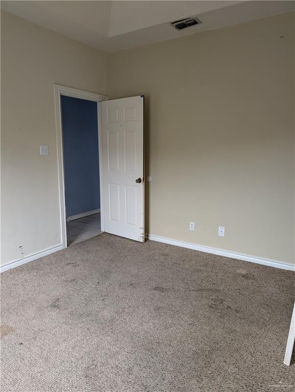 carpeted spare room featuring baseboards and visible vents