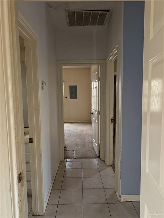 hallway with light tile patterned floors, baseboards, and visible vents