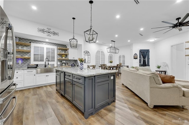 kitchen featuring white cabinets, a center island, light stone counters, hanging light fixtures, and gray cabinets