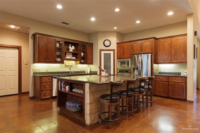 kitchen with appliances with stainless steel finishes, a kitchen breakfast bar, dark stone counters, sink, and a center island