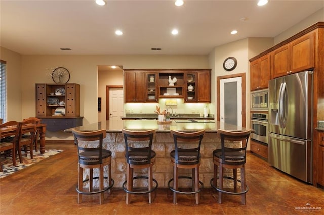 kitchen featuring a breakfast bar, a center island, stainless steel appliances, and dark tile patterned floors