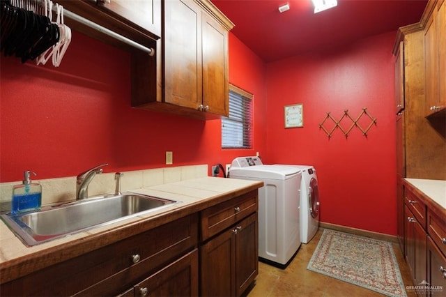 clothes washing area with cabinets, sink, and washing machine and clothes dryer