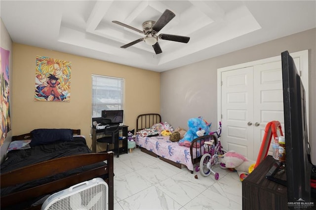 bedroom featuring ceiling fan, a tray ceiling, and a closet