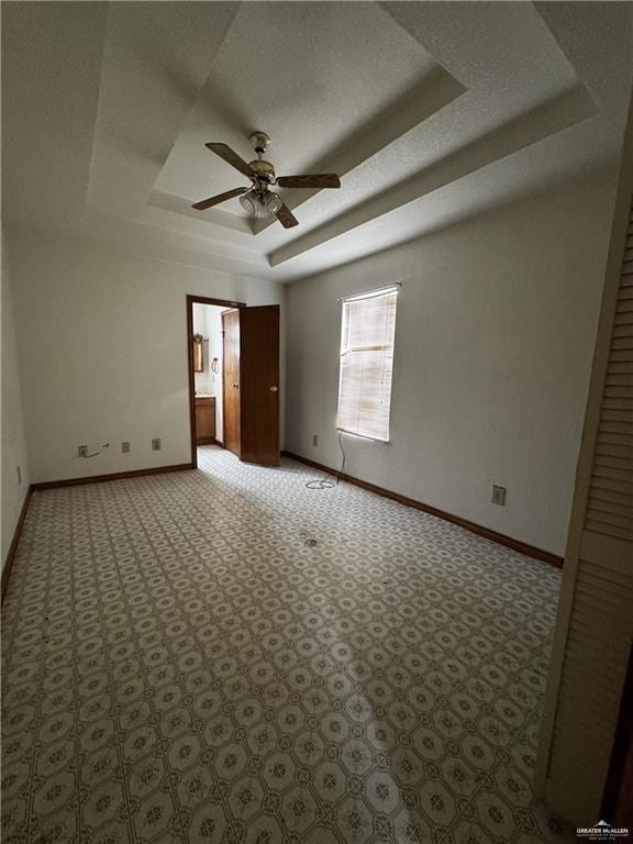 empty room featuring ceiling fan and a tray ceiling