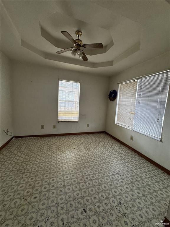 empty room featuring ceiling fan and a tray ceiling