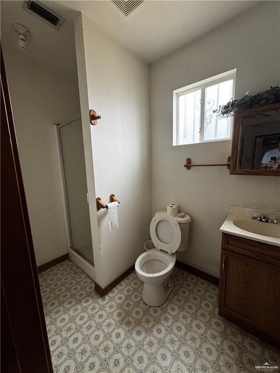 bathroom featuring vanity, an enclosed shower, and toilet