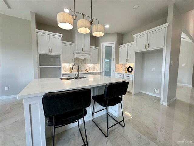 kitchen with white cabinets, pendant lighting, a kitchen island with sink, and sink