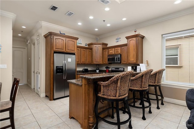 123 E Saturn Ln Unit C-3, South Padre Island, TX 78597 - kitchen with stainless steel appliances, light tile patterned floors, a kitchen breakfast bar, a peninsula, and crown molding