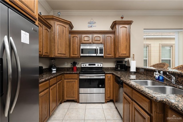123 E Saturn Ln Unit C-3, South Padre Island, TX 78597 - kitchen featuring appliances with stainless steel finishes, ornamental molding, light tile patterned flooring, brown cabinets, and dark stone counters