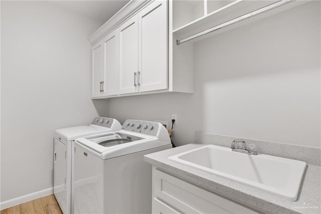 laundry area featuring washer and dryer, cabinets, light wood-type flooring, and sink