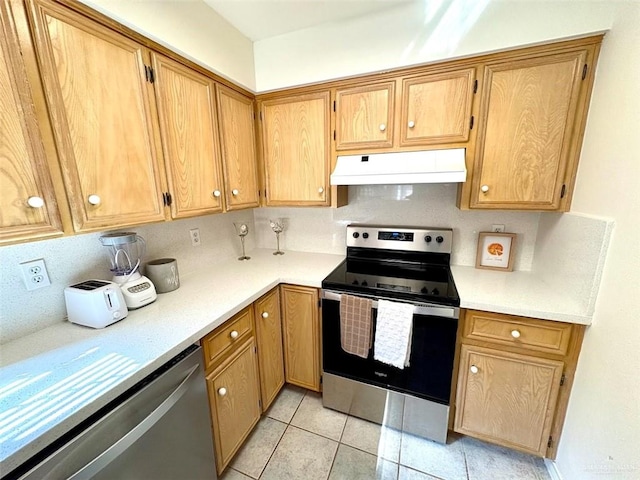 kitchen with light countertops, light tile patterned floors, stainless steel appliances, under cabinet range hood, and backsplash