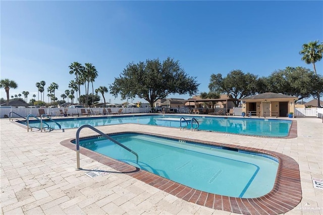pool with a patio and fence