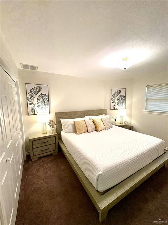 bedroom featuring visible vents, a closet, and dark colored carpet