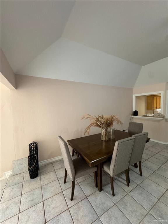 dining area featuring light tile patterned flooring, baseboards, and vaulted ceiling