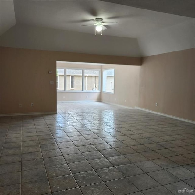 interior space featuring a ceiling fan, dark tile patterned floors, baseboards, and lofted ceiling