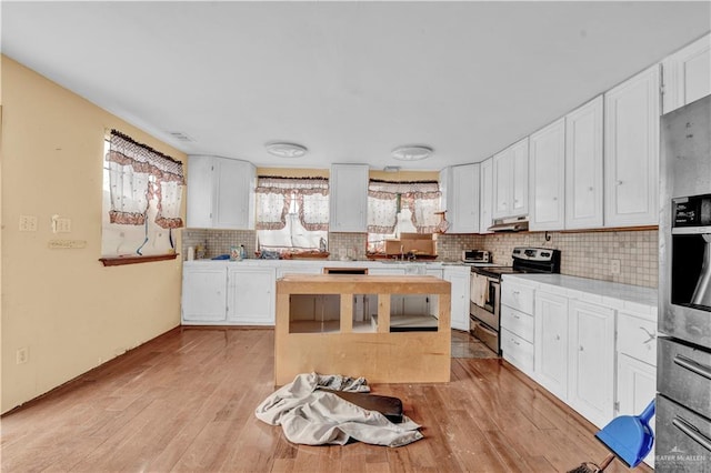 kitchen featuring tasteful backsplash, white cabinets, light countertops, stainless steel range with electric cooktop, and under cabinet range hood