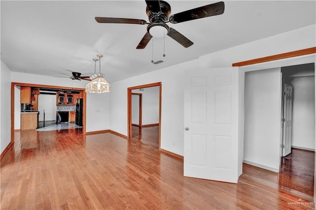 unfurnished living room with wood finished floors, a ceiling fan, and baseboards