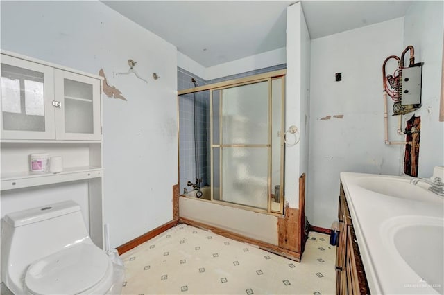 full bathroom featuring double vanity, bath / shower combo with glass door, toilet, a sink, and baseboards