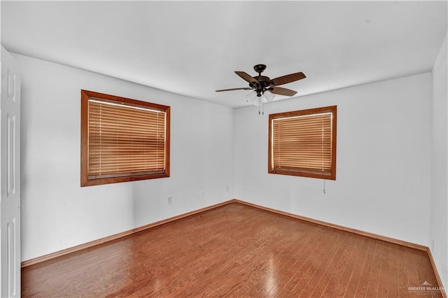 empty room featuring a ceiling fan, baseboards, and wood finished floors