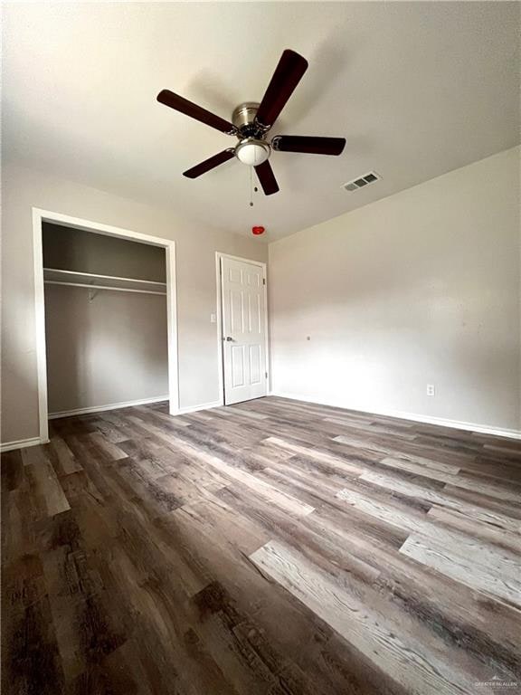 unfurnished bedroom with ceiling fan, dark hardwood / wood-style floors, and a closet