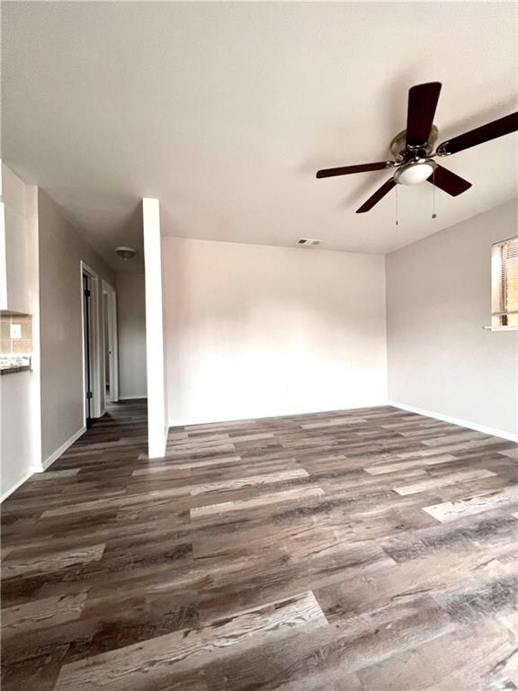 empty room with ceiling fan and dark wood-type flooring