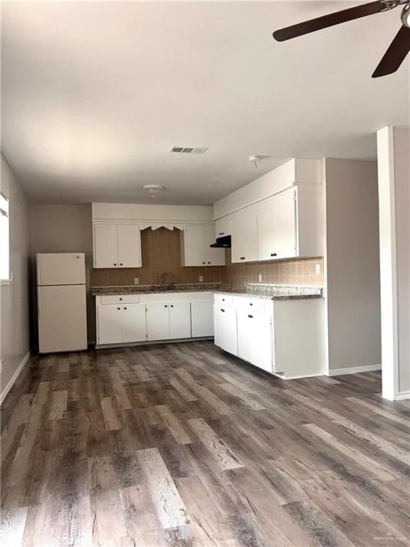 kitchen with white cabinetry, sink, dark wood-type flooring, white refrigerator, and decorative backsplash