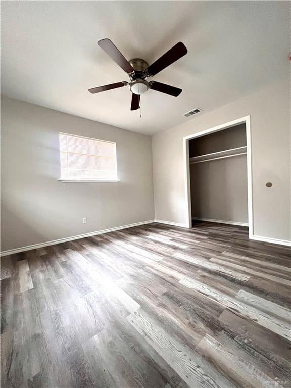 unfurnished bedroom featuring hardwood / wood-style floors, ceiling fan, and a closet