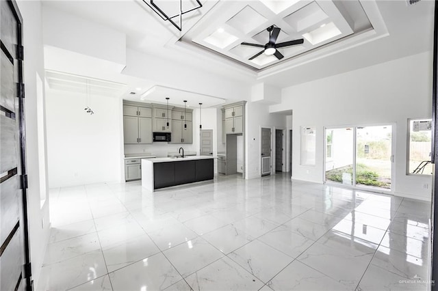 kitchen with ceiling fan, sink, decorative light fixtures, a center island with sink, and gray cabinets