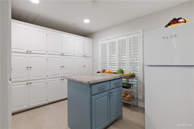 kitchen with white fridge, a kitchen island, and white cabinetry