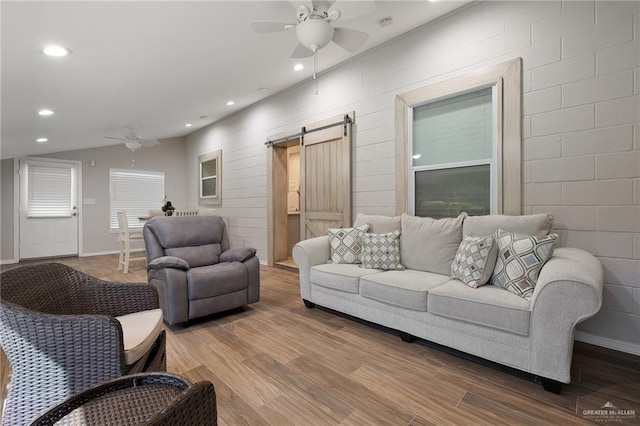 living room with hardwood / wood-style floors, a barn door, and ceiling fan