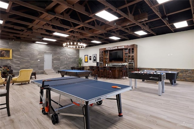 game room with light hardwood / wood-style floors, tile walls, bar, and pool table