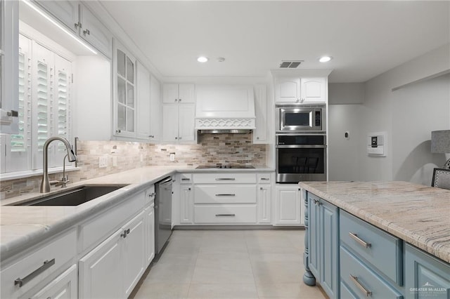 kitchen featuring blue cabinetry, white cabinetry, light stone countertops, stainless steel appliances, and decorative backsplash