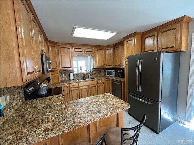 kitchen with black appliances, sink, a kitchen breakfast bar, decorative backsplash, and kitchen peninsula