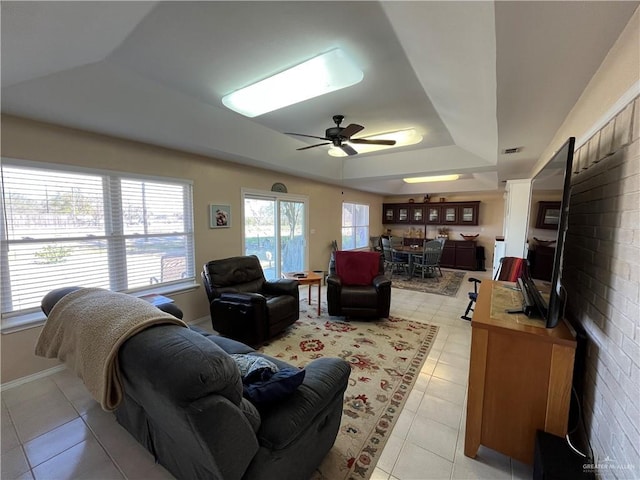 living room featuring light tile patterned floors, a raised ceiling, and ceiling fan