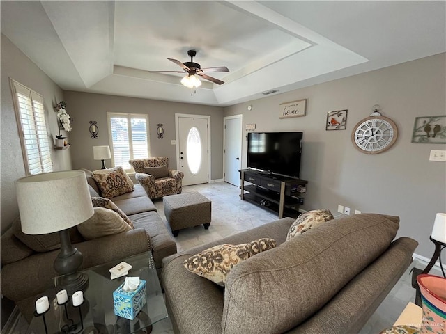 living room with a raised ceiling and ceiling fan