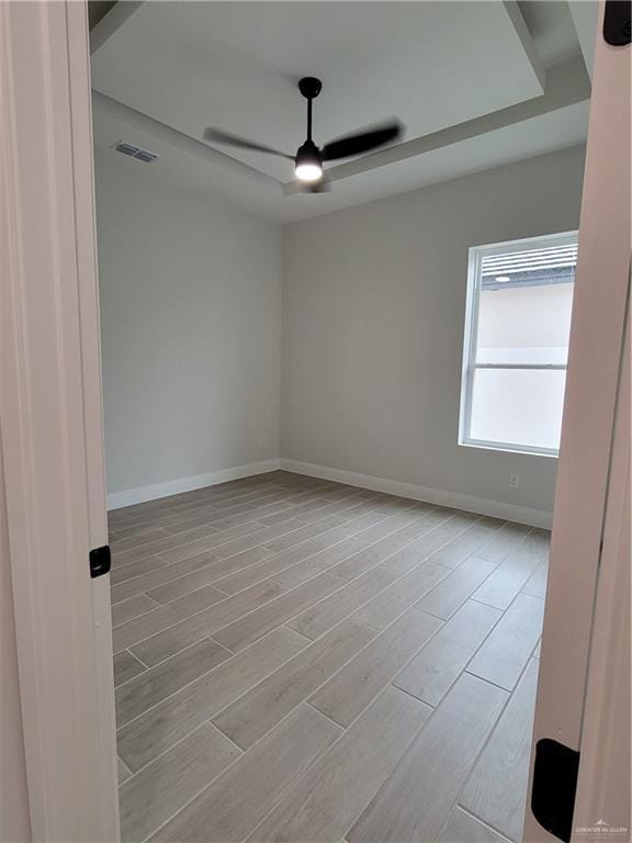 spare room featuring baseboards, visible vents, wood finished floors, and a ceiling fan
