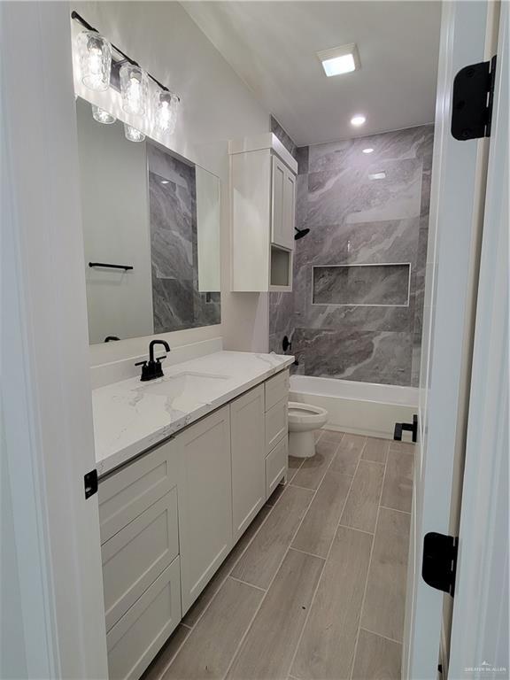 bathroom with toilet, vanity, shower / tub combination, and wood tiled floor