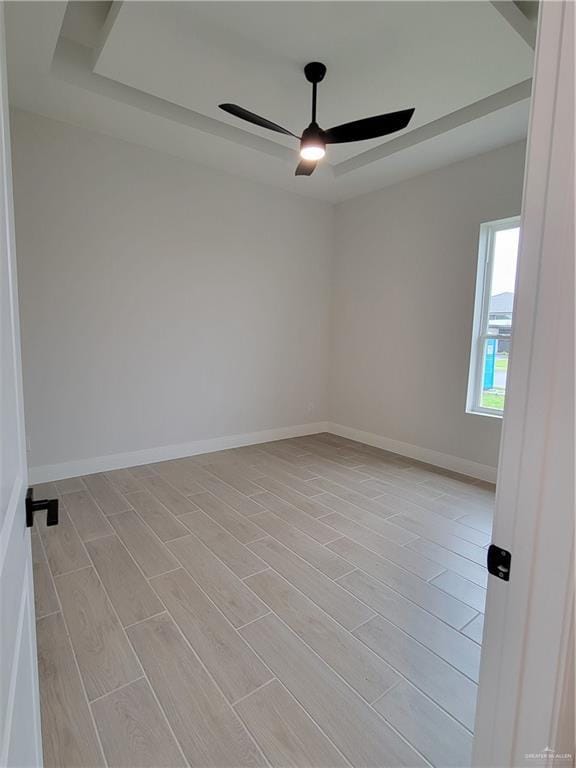spare room with baseboards, light wood finished floors, and ceiling fan