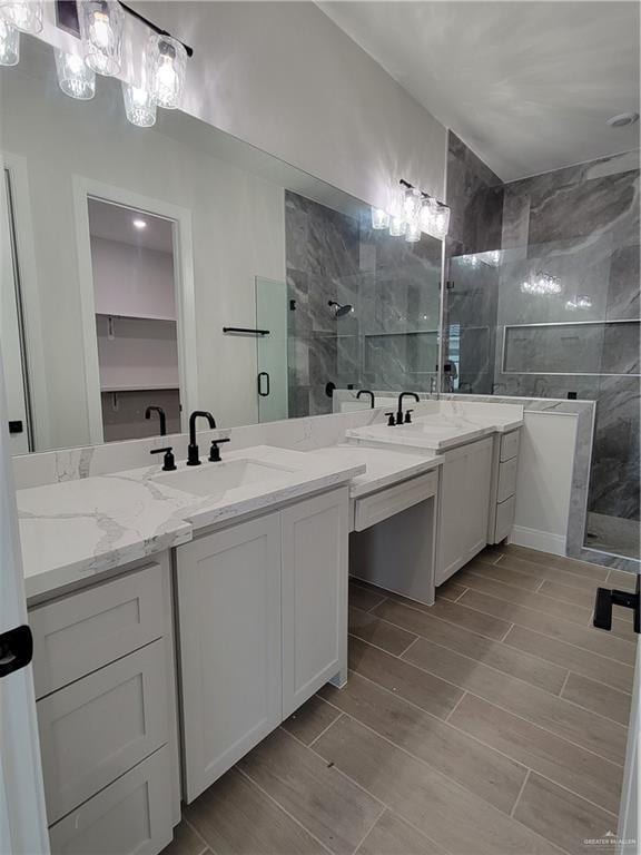 full bathroom featuring a sink, a tile shower, and wood finish floors